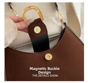 Dettaglio della chiusura magnetica dorata su una borsa vintage in pelle scamosciata marrone
