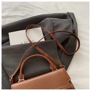 Brown leather handbag styled on a grey blazer with artistic book for a trendy aesthetic look