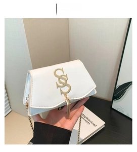 Détail du petit sac blanc carré avec boucle dorée en S et pompon à chaîne élégant