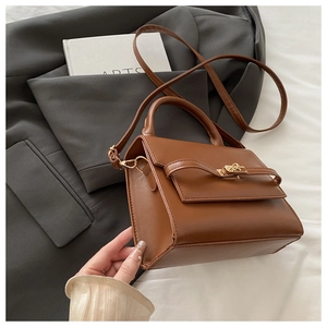Detail of a brown vintage leather handbag with metallic clasp on a dark grey blazer
