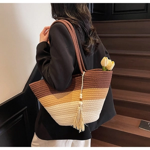 Detail of hand-woven striped straw tote bag with brown tassel and gradient texture
