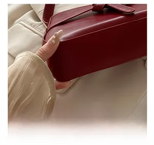 Detailed macro view showing the precision stitching on a dark red leather shoulder bag