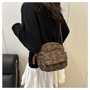 Sac bandoulière en velours côtelé marron avec imprimés nœuds porté par un mannequin