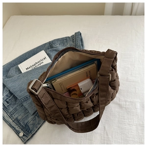 Spacious interior of a dark brown quilted puffer bag with books and daily essentials