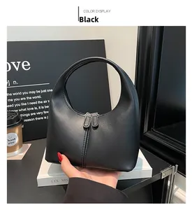 Close-up of black matte leather dumpling bag with minimalist handle and dual zippers
