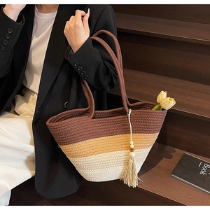 Close-up of three-color woven straw tote bag with cotton tassels and wood bead detail