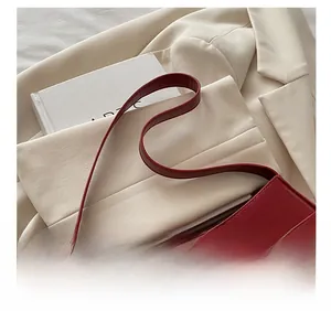 Detail view of red PU leather shoulder bag with adjustable strap and golden metal buckle