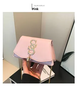 Détail du sac à bandoulière rose avec fermoir doré à lettres et bandoulière chaîne
