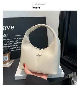 Detail of a minimalist cream white hobo handbag with metal double zippers and smooth finish
