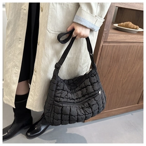 Detail of black quilted puffer bag with zipper pocket and adjustable strap in cafe setting