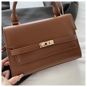 Close-up of brown faux leather handbag with classic golden twist lock and top handle