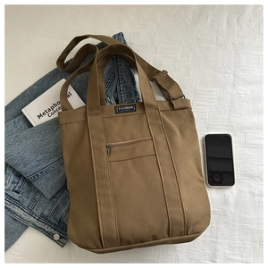 Sac cabas en toile marron avec bandoulière réglable près d'une veste en jean