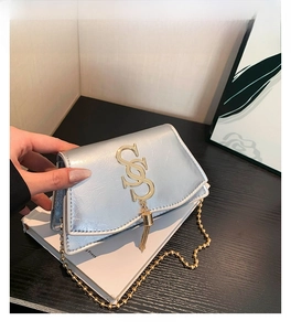 Détail du sac bandoulière en cuir argenté froissé avec logo doré et pompon