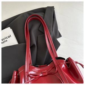 Detail of red patent leather tote bag with glossy finish and bow tie decoration
