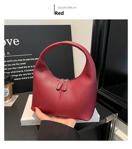 Detailed macro view of the red leather handbag featuring dual zippers and fine stitching