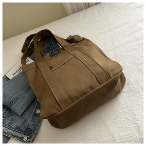 Détail du sac cabas en toile marron avec poche zippée et étiquette tissée fashion