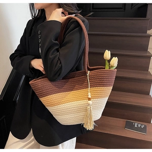 Detail of woven straw tote bag with three-tone stripes and long boho tassel charm