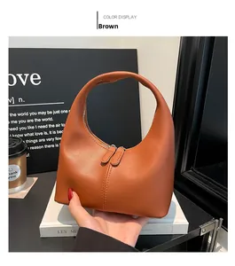 Close-up of brown crescent handbag featuring dual zippers and smooth leather texture