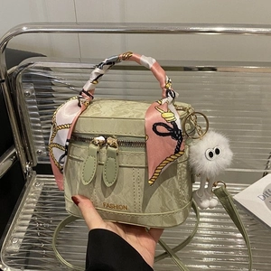 Pale green structured fashion handbag with silk scarf handle and plush monster charm