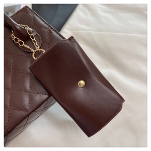 Detail of dark brown quilted leather handbag with gold chain and matching mini pouch