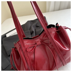 Detail of red patent leather tote bag with drawstring closure and bow decoration