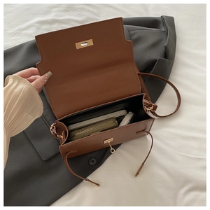 Detail view of large interior capacity of brown crossbody bag with gold turn-lock hardware