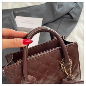Close-up of quilted dark chocolate handbag with gold chain and round handle detail