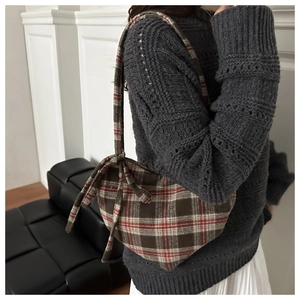Détail du sac à carreaux rétro avec un nœud élégant sur une texture en tissu épais