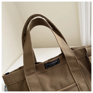 Détail du sac cabas marron en toile avec étiquette Fashion Instinct et zip lisse