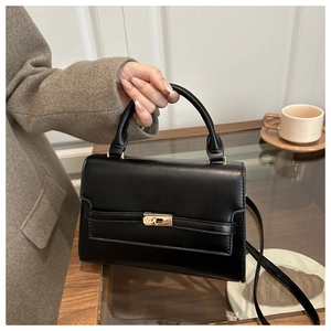 Classic black trapezoid bag featuring gold buckle details and elegant top handle design