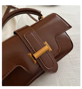 Macro detail of brown leather handbag with vintage bronze buckle and stitching
