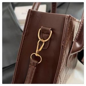 Detailed close-up of dark chocolate quilted leather bag with gold metal lobster clasp and D-ring
