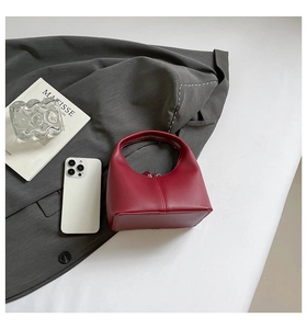 Top view of a glossy wine red mini handbag with a sleek curved handle and zipper closure