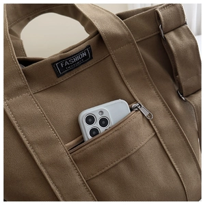 Gros plan du sac cabas en toile avec poche zippée externe et étiquette de mode