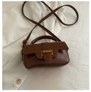 Detail view of brown glossy leather crossbody bag with gold buckle and size reference