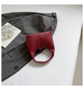 Top view of smooth dark red crescent handbag with double zipper and stylish office props