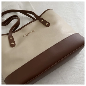 Detail of the golden bow clasp and high-quality leather texture on the tote bag