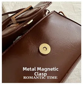 Detailed macro view of the golden magnetic snap button on a brown leather shoulder bag