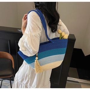 Detailed close-up of gradient blue woven tote bag with fringe tassel and tulip decor