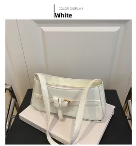 Detail view of white faux leather underarm bag with gold buckle and slim strap