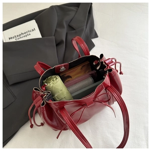 Deep red patent leather tote bag interior view with drawstring bow and large capacity