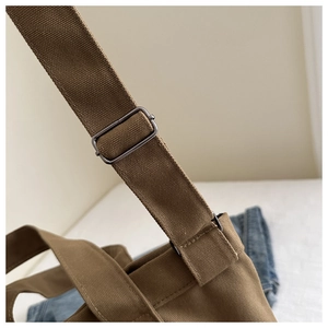 Détail de la bandoulière en toile marron foncé avec boucle en métal gris réglable