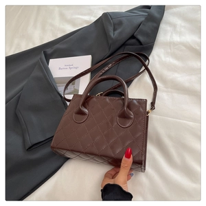 Detailed view of a brown quilted leather crossbody bag on a modern urban lifestyle backdrop