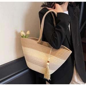 Detail of gradient woven straw tote bag with tassel and beads for summer beach vacations