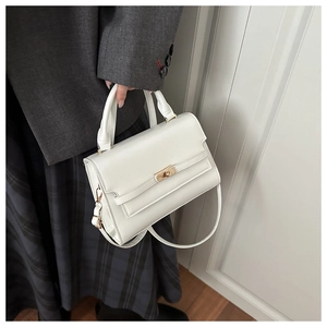 Detailed close-up of a white leather crossbody bag featuring a golden metallic twist lock