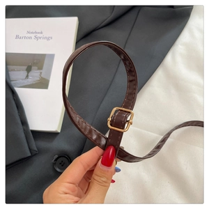 Close-up of adjustable dark brown leather shoulder strap with gold square metal buckle