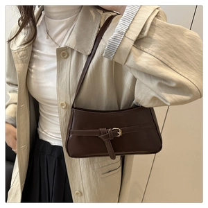 Dettaglio della borsa a spalla in pelle marrone scuro con fibbia decorativa e oro metallo