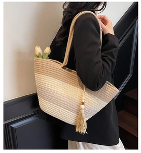 Detail of striped straw tote bag featuring tassel accents and wooden beads for beach travel