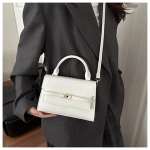 Detailed close-up of white leather handbag with golden twist lock and round handle