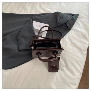 Deep brown quilted tote bag set with small matching zip pouch on soft white bedding